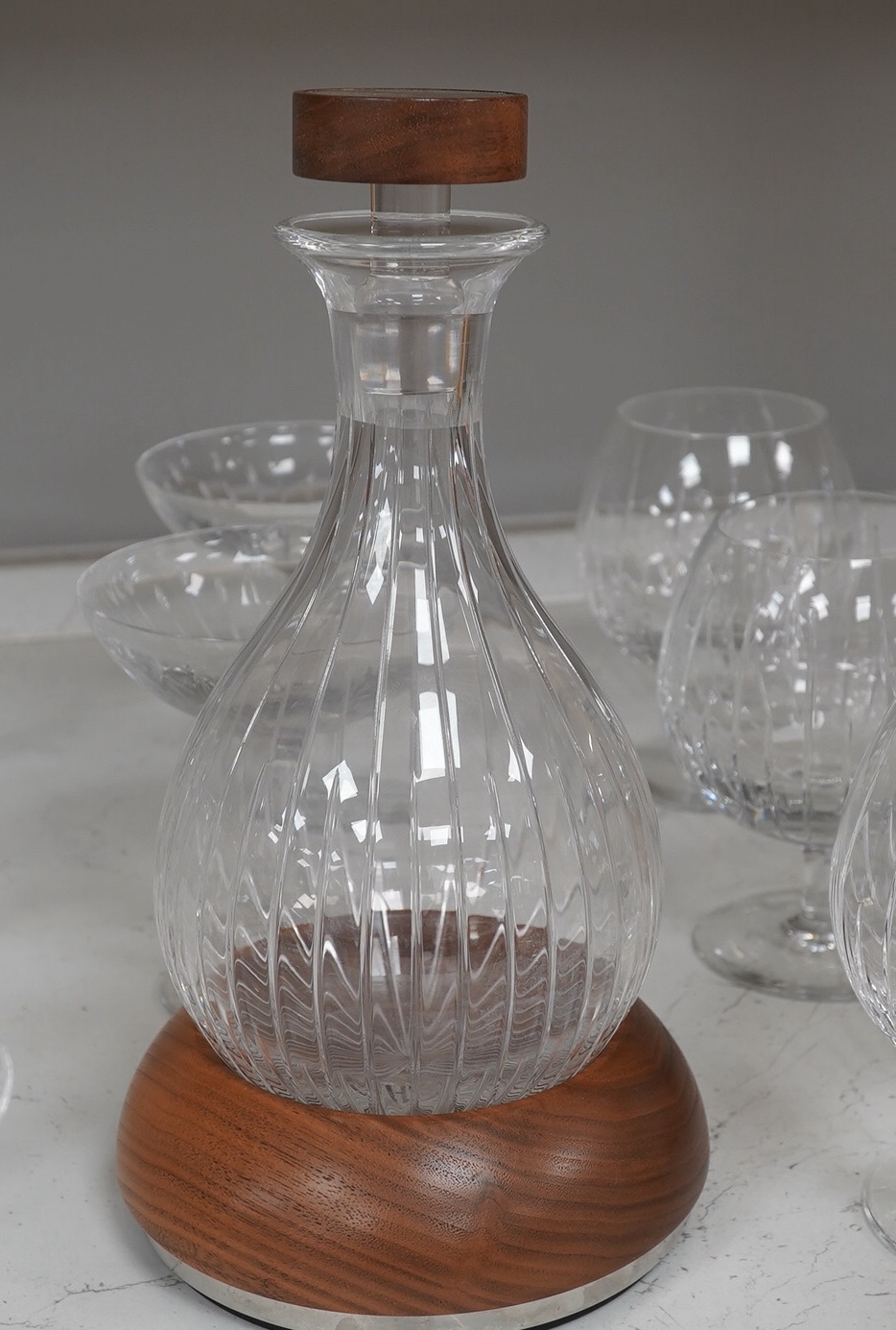 A Linley Glyndebourne pattern cut glass decanter with a silver mounted stopper, on a weighted wooden coaster stand, and a matching set of ten goblets and eight champagne coupes, largest 30cm high. Condition - all in very